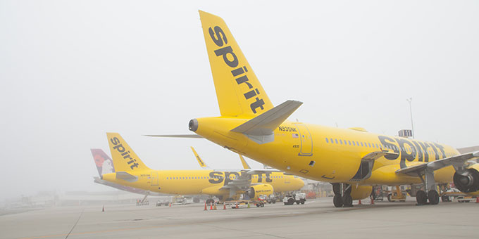 three yellow spirit airlines planes in fog